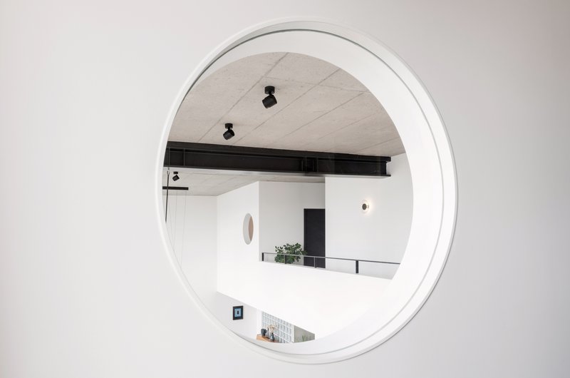 Das Bullauge als verbindendes Element zwischen Wohnraum und Bad im Loft Zürich.